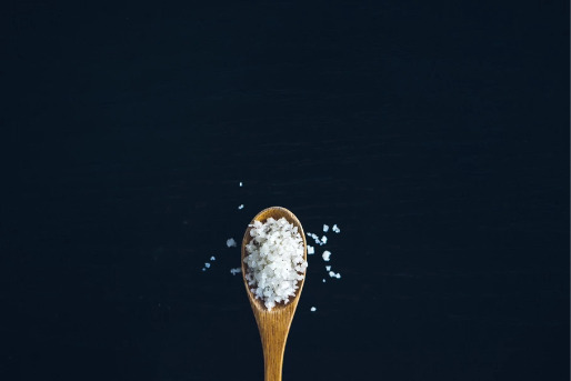 Salt spoon with salt overflowing.