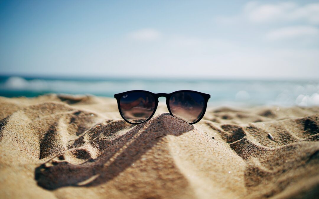 Sunglasses on a mound of sand at the beach.