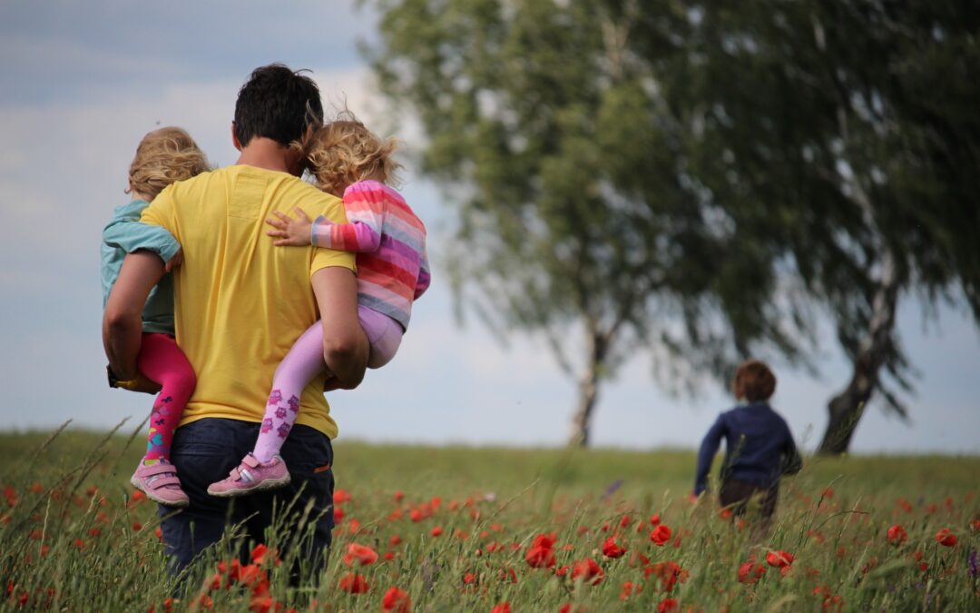 Man walking with children through a field.